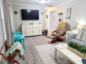 A living room with a TV, a sofa, a chair, a table, and a cabinet. - No Cleaning Fee - Steps to Entertainment - King Bed - Family Friendly (Newport)