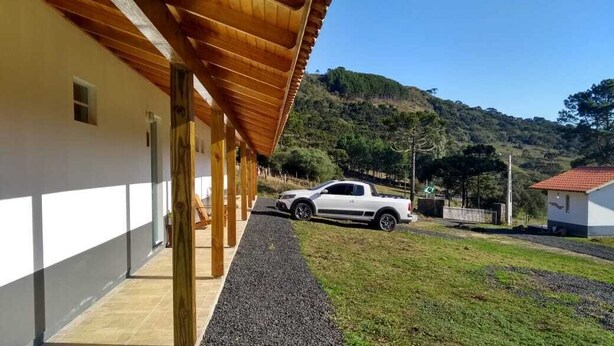 A building with a covered walkway and a white pickup truck parked in front. - Pousada Aurora (Urubici)