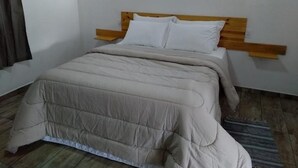 A bedroom with a bed, wooden headboard, two wall-mounted lights, and a striped rug. - Pousada Aurora (Urubici)