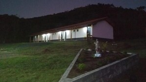 A building with a sloped roof and a small garden area with a statue. - Pousada Aurora (Urubici)