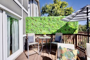 Een terras met een tafel, stoelen, een potplant en een houten leuning.