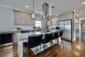 Una cocina moderna con armarios blancos, electrodomésticos de acero inoxidable y una isla central con taburetes de bar.