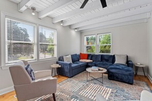 A modern living room with a sectional sofa, a round coffee table, and a patterned rug. - Downtown Raleigh | Sleeps 15 | Game Yard & Parking (Raleigh)
