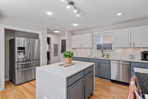 A modern kitchen with stainless steel appliances, grey cabinets, and a central island.