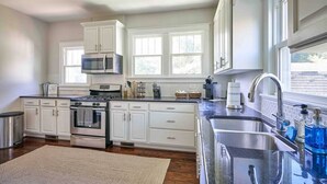 A kitchen with white cabinets, a stove, oven, microwave, and a large sink. - Downtown Raleigh: Spacious, Pet-Friendly, Fenced (Raleigh)