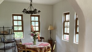 Un coin repas avec une table en bois, des chaises, un lustre et une bibliothèque.
