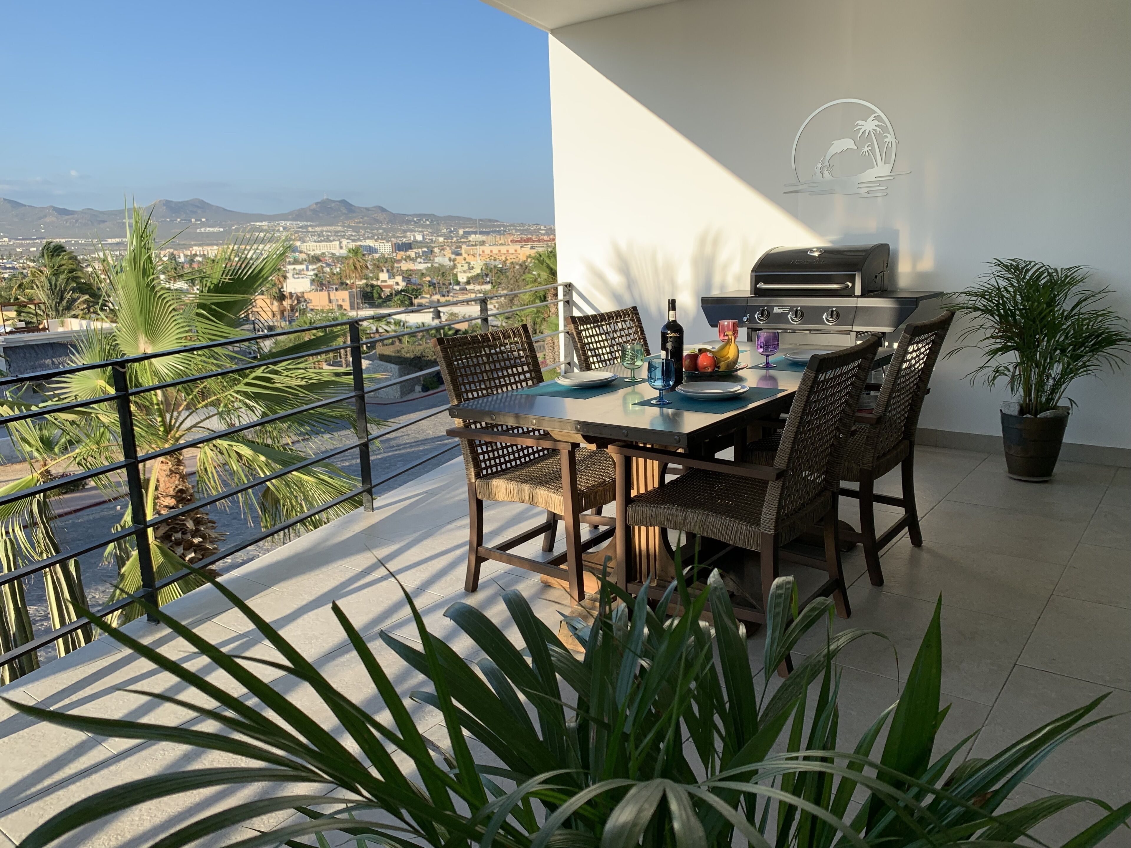 Ein Balkon mit Tisch für vier Personen, einem Grill und Topfpflanzen.