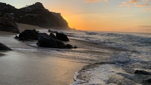 Paesaggio costiero con spiaggia, onde e tramonto.