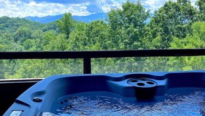 Ein Whirlpool mit Blick auf eine Berglandschaft und einen dichten Wald.