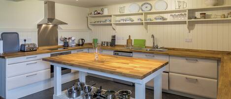 A modern kitchen with a wooden island, stainless steel appliances, and white cabinetry.