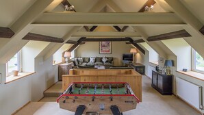 A loft-style room with a foosball table, a sofa, and a television.