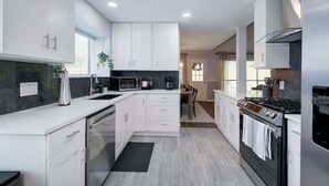 A modern kitchen with white cabinetry, a built-in microwave, a stove, and a dishwasher. - Hot Tub | Sauna | Pets Allowed | Sleeps 10 (Leander)