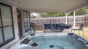 A backyard with a hot tub, a covered patio, a sofa, and a grill. - Hot Tub | Sauna | Pets Allowed | Sleeps 10 (Leander)