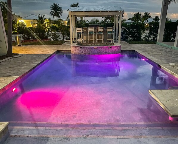 Piscina com deck revestido e área de estar coberta.