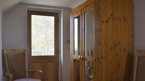 Ein Zimmer mit Holztür, einem Fenster und zwei Holzsesseln.
