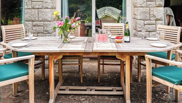 A wooden table set for two with a vase of flowers, a bottle of champagne, and a pitcher of drinks. - 5 bedroom accommodation in Chilcompton (Chilcompton)