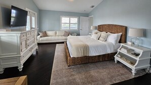 A bedroom with a large bed, a dresser, a television, and a nightstand.