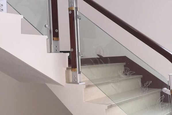 A modern staircase with glass railings and wooden handrails.