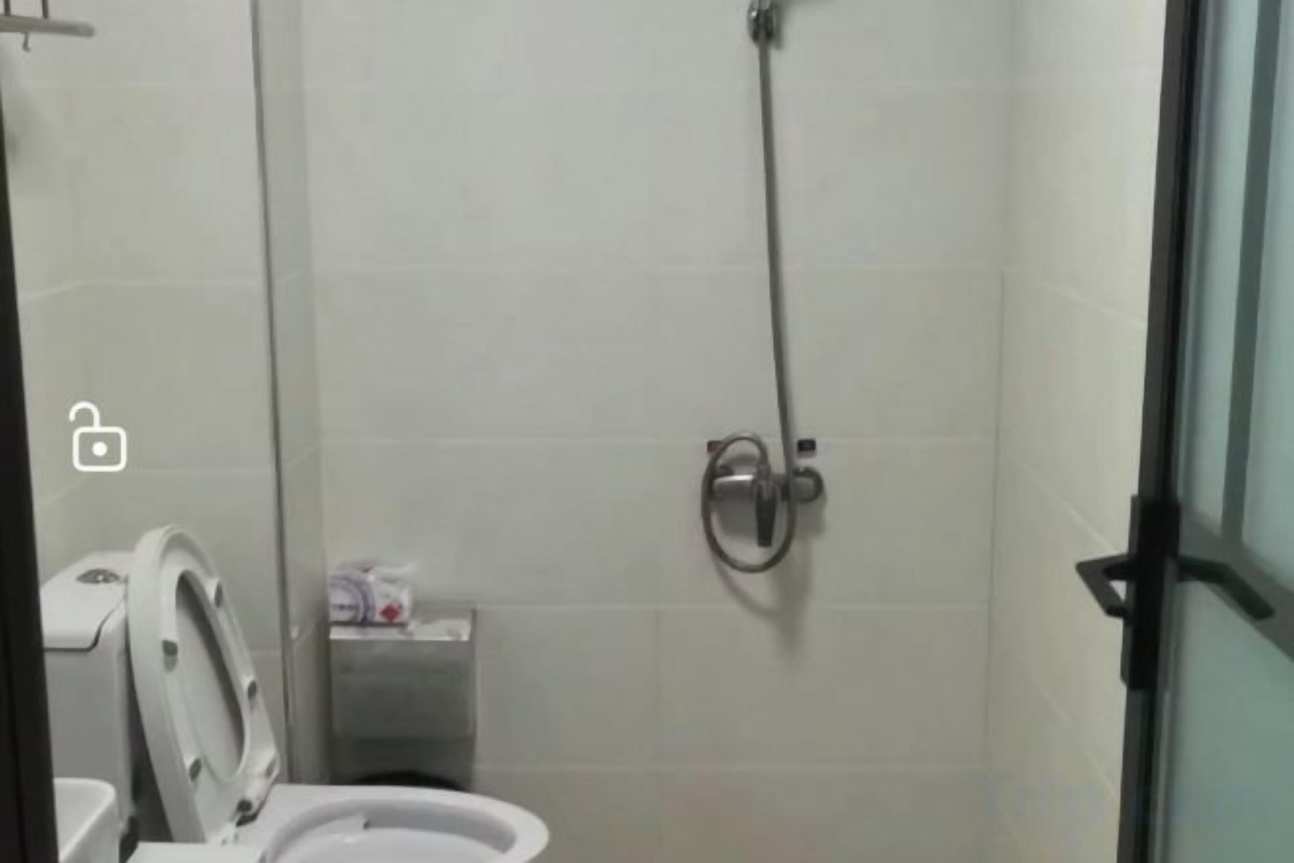 A bathroom with a toilet, a shower, and a hand dryer.