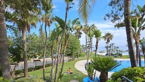 A pathway leading to a pool area with palm trees and a clear sky.