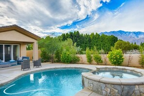 Une piscine avec un jacuzzi, un espace salon extérieur et une vue imprenable sur les montagnes.