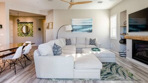 A modern living room with a sectional sofa, a dining area with a wooden table, and a fireplace.