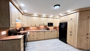 Une cuisine moderne avec des meubles en bois clair, des appareils en acier inoxydable et un sol carrelé de couleur grise.
