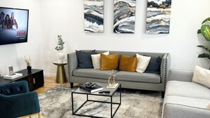 Un salon moderne avec un canapé gris, une table basse et un téléviseur fixé au mur.