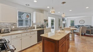 A modern kitchen with white cabinetry, a central island, and pendant lighting.