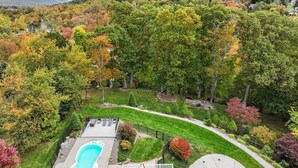 A residential area with a swimming pool, a patio with seating, and a well-maintained lawn.