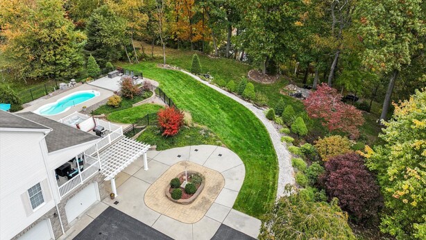 A residential property with a swimming pool, a covered patio, and a well-maintained lawn.