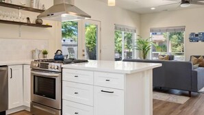 Een moderne keuken met witte kasten, een ingebouwde oven en een groot eiland met lades.
