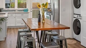 Een moderne keuken met een houten tafel, barstoelen, een ingebouwde oven en een wasmachine.