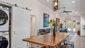 Een moderne keuken met een houten tafel, barstoelen en een plafondventilator.