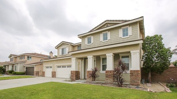 A two-story house with a front porch, garage, and a well-maintained lawn. - This house is a 5 bedroom(s), 3 bathrooms, located in Eastvale , CA. (Eastvale)