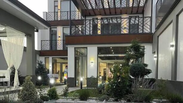 Een modern buitenontbijtgedeelte met een vuurplaats, een zithoek en uitzicht op het interieur van het gebouw.