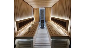 A sauna with wooden benches and a central heating unit.