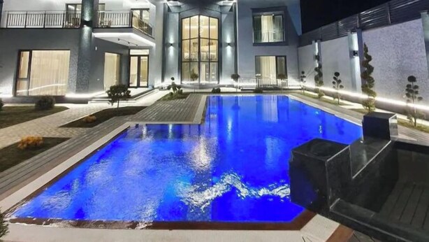 A modern house with a swimming pool at night.