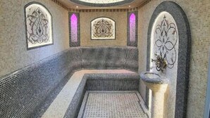 A spa room with a curved bench, mosaic walls, and a patterned floor.