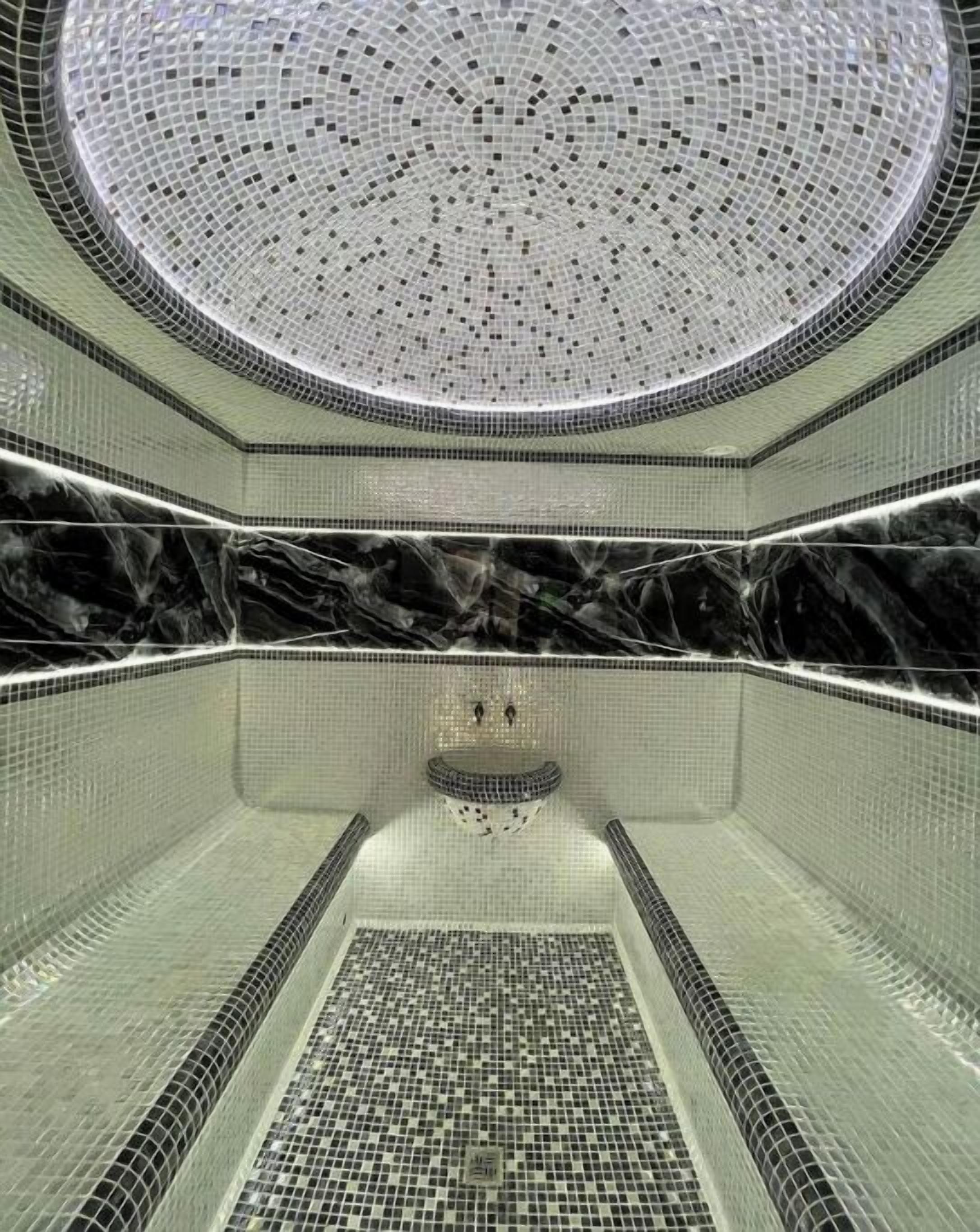 Een moderne badkamer met een rond dakraam, een marmeren wastafelmeubel en een betegelde vloer.