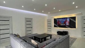 A modern living room with a grey sectional sofa, a coffee table, and a flat-screen TV mounted on the wall. - Villa "Ustoz" in Chorvoq, Tashkent (Тошкент)