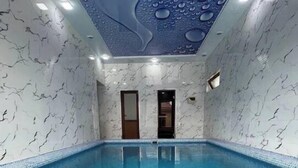 An indoor swimming pool with a clear blue water surface, surrounded by walls with a marble-like pattern. - Villa "Ustoz" in Chorvoq, Tashkent (Тошкент)