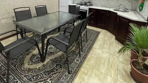 A compact kitchen with a dining table, chairs, a refrigerator, and cabinets. - Rapunzel villa (Тошкент)