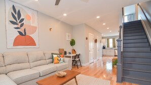 A spacious living room with a sofa, coffee table, and a staircase leading to another level. - Minutes to Downtown & Waterfronts with rooftop deck! (Baltimore)