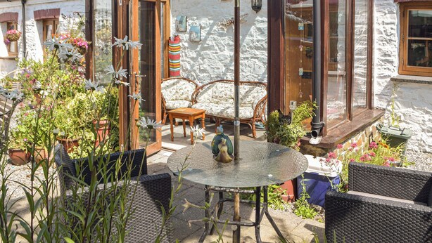 A patio with wicker furniture, a round table, and a green umbrella. - Picked for its charm and character and close to a plethora of walks. (Crundale, near Haverfordwest)