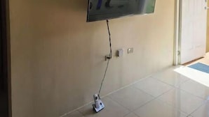 Ein an der Wand befestigter Fernseher in einer Diele mit Fliesenboden.