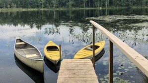 Une jetée en bois avec deux kayaks jaunes et un canoë blanc.