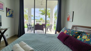 A hotel room with a bed, a TV, a desk, and a balcony with chairs and a table.