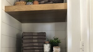 Un estante de madera escalonado con toallas dobladas, plantas en macetas y objetos decorativos.