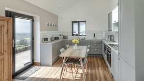 A modern kitchen with a skylight, a dining area with a wooden table, and grey cabinetry.